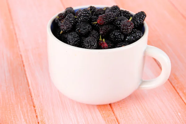 Ripe mulberries in cup on wooden background — Stock Photo, Image