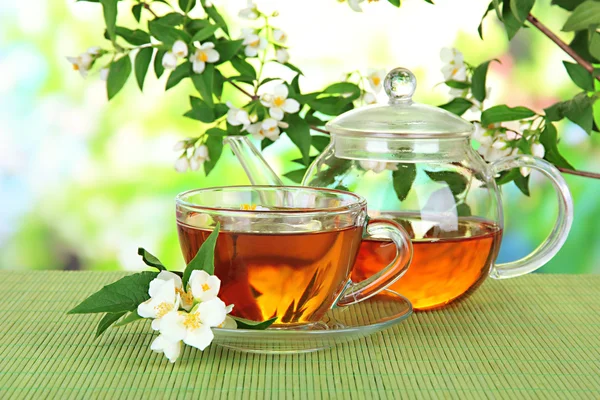 Cup of tea with jasmine, on bamboo mat, on bright background — Stock Photo, Image