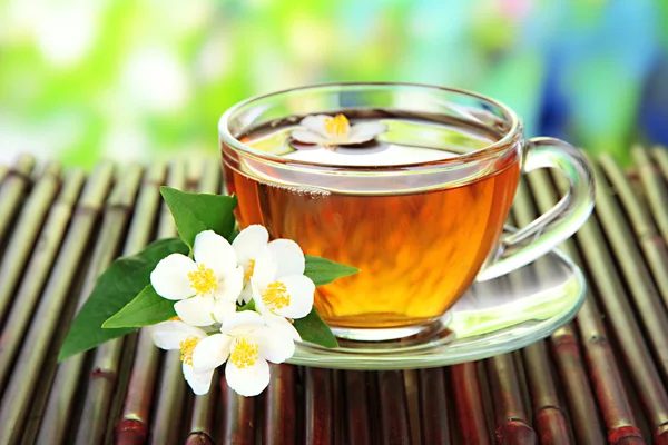 Чашка чая с жасмином, на бамбуковом коврике, крупным планом — стоковое фото