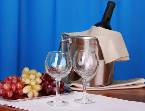 Vin og glass på rundbord på tekstilbakgrunn – stockfoto