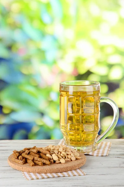 Bière en croque de verre, et noix sur la serviette sur la table sur fond de nature — Photo