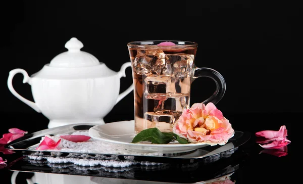 Glass cup of ice tea from tea rose on metallic tray on napkin on black background — Stock Photo, Image