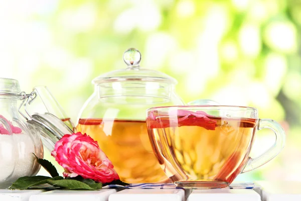 Vattenkokare och kopp te från tea rose på servett på träbord på natur bakgrund — Stockfoto
