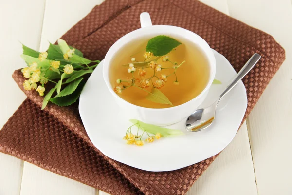 Kopje thee met linden op servet op houten tafel — Stockfoto
