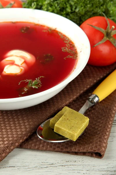 Ciotola di zuppa con cubetti di brodo sul tavolo di legno — Foto Stock