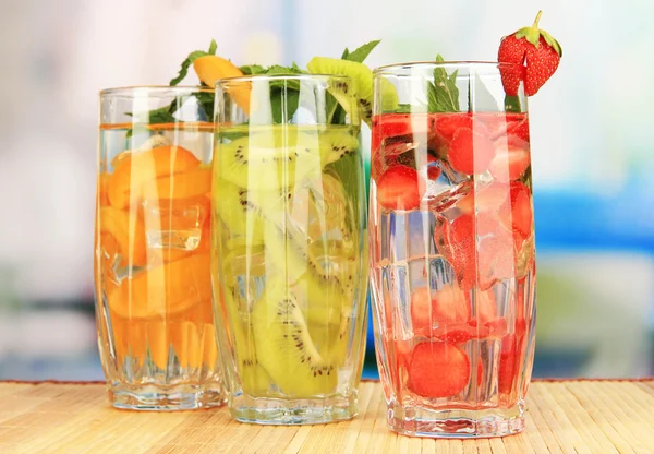 Glasses of fruit drinks with ice cubes on table in cafe — Stock Photo, Image