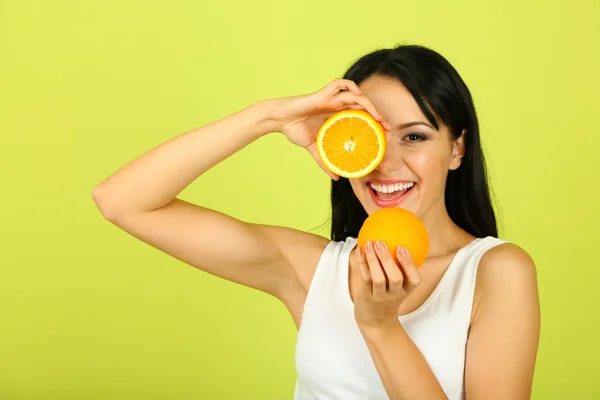 Menina com suco fresco e laranja no fundo verde — Fotografia de Stock