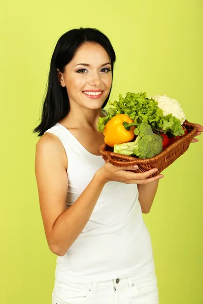 Meisje met groenten op groene achtergrond — Stockfoto