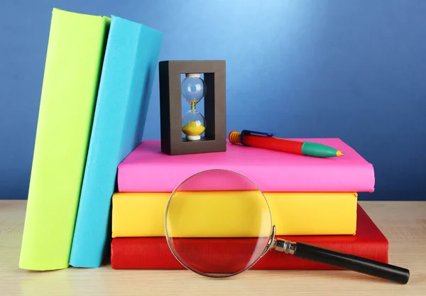 Livres de couleur avec loupe sur table sur fond bleu — Photo