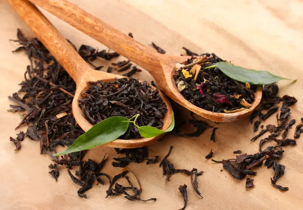 Dry tea with green leaves in wooden spoons, on wooden background — Stock Photo, Image