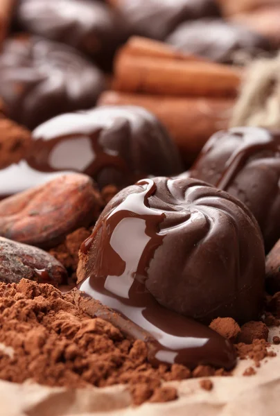 Состав шоколадных конфет, какао и специй на коричневом фоне — стоковое фото