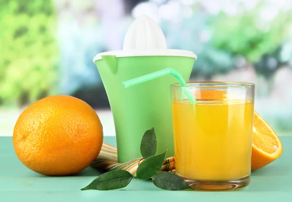 Citruspress, glas juice och mogna apelsiner på gröna träbord — Stockfoto