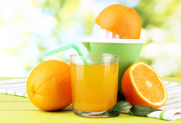 Prensa cítrica, vaso de jugo y naranjas maduras sobre mesa de madera blanca — Foto de Stock