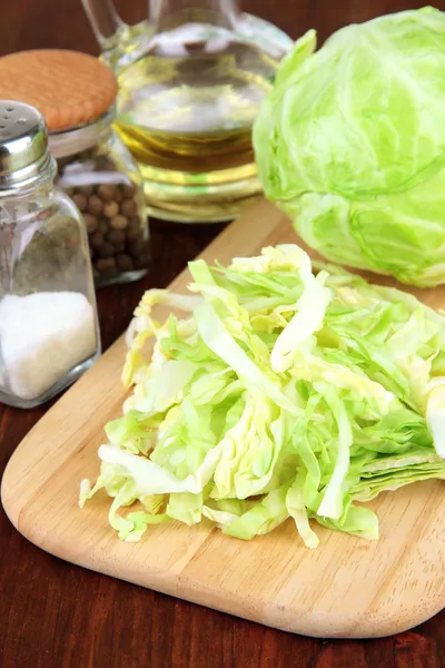 Green cabbage, oil, spices on cutting board, on wooden background — Stock Photo, Image