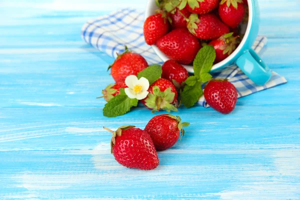 Reife süße Erdbeeren im Becher auf blauem Holztisch — Stockfoto