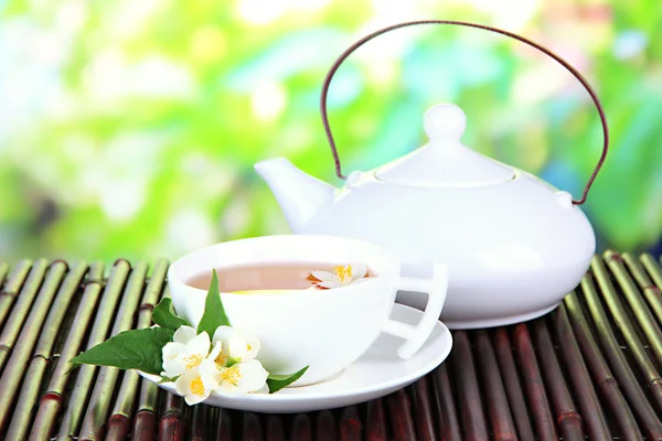 Cup of tea with jasmine, on bamboo mat, on bright background — Stock Photo, Image