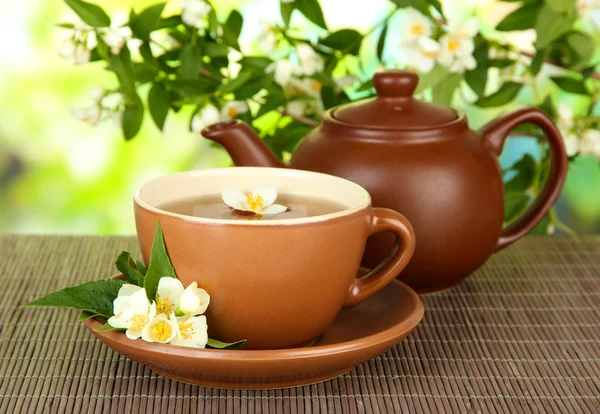 Cup of tea with jasmine, on bamboo mat, on bright background — Stock Photo, Image