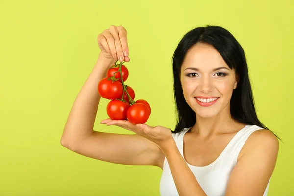 Girl with fresh tomatoes on green background — Stock Photo, Image