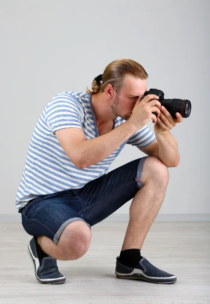Knappe fotograaf met camera, op grijze achtergrond — Stockfoto