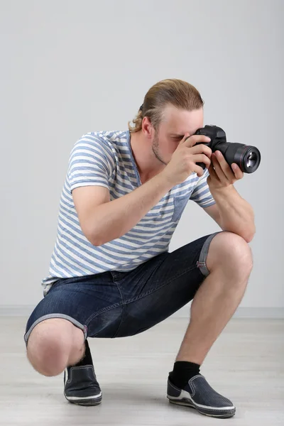 Handsome photographer with camera, on gray background — Stock Photo, Image