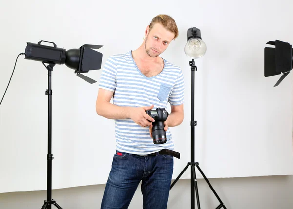 Stilig fotograf med kamera på arbetar, på foto studio bakgrund — Stockfoto