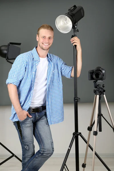 Handsome photographer with camera at working, on photo studio background — Stock Photo, Image