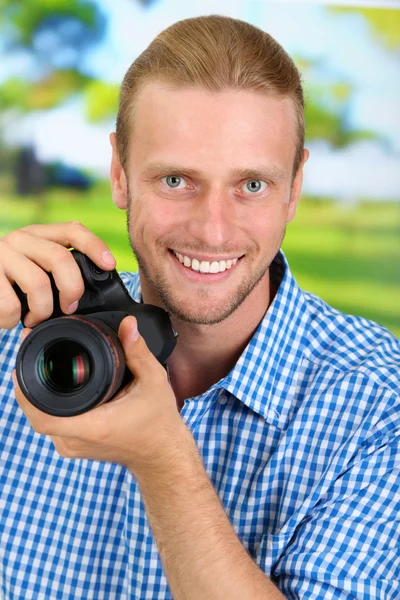 Knappe fotograaf met camera, op lichte achtergrond — Stockfoto