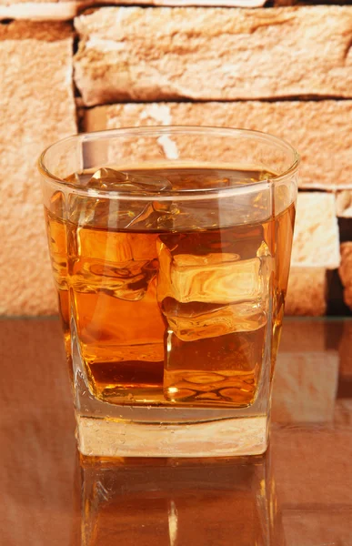 Glass of whiskey and ice on brick wall background — Stock Photo, Image