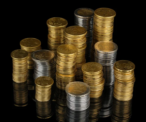 Many coins in columns isolated on black — Stock Photo, Image