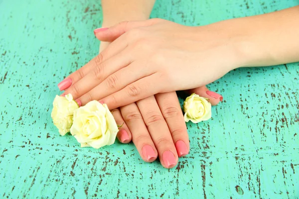 Жінка руки з рожевим манікюром і квітами, на кольоровому фоні — стокове фото