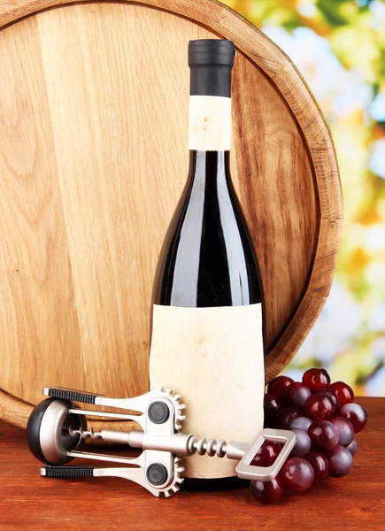 コルクせん抜き、ワイン、ブドウ、明るい背景に木製のテーブルの上に木製の樽のボトル入りの組成 — ストック写真