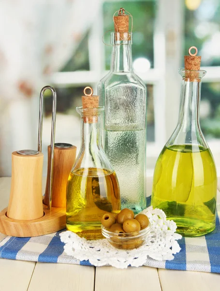 Bottiglie di vetro originali con condimento per insalata su tavolo in legno su sfondo finestra — Foto Stock