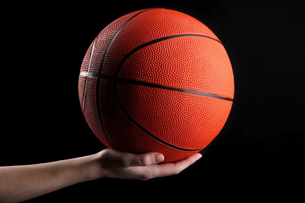 Basketball in woman hand on black background — Stock Photo, Image