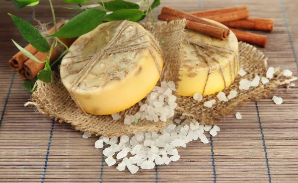 Hand-made soap and sea salt on grey bamboo mat — Stock Photo, Image