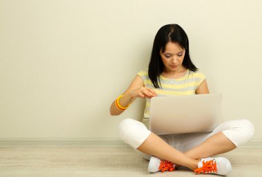 Odada dizüstü bilgisayar ile oturup güzel bir genç kadın