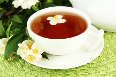 Cup of tea with jasmine, on wicker mat background