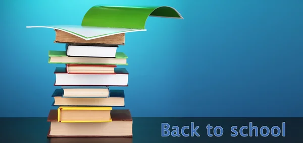 Stack of interesting books and magazines on wooden table on blue background — Stock Photo, Image