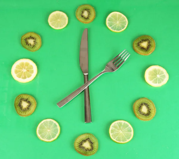 Clock made of kiwi, lime and lemon slices, on color background — Stockfoto