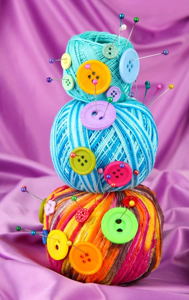 Botones coloridos y bolas de lana multicolor, sobre fondo de tela de color —  Fotos de Stock