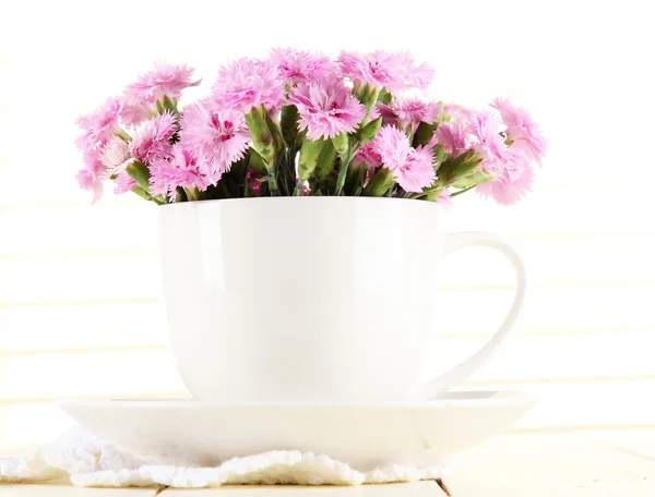 Muchos pequeños dientes de color rosa en taza sobre fondo de madera — Foto de Stock