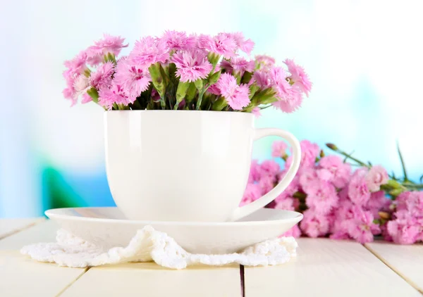 Viele kleine rosa Nelken in Tasse auf Holztisch auf Fensterhintergrund — Stockfoto