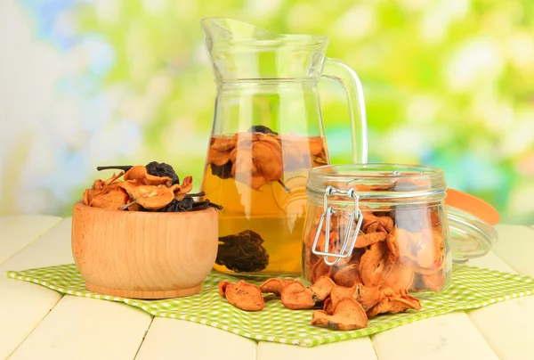 Assorted dried fruits in bowl and compote of dried fruits on wooden table on natural background — Stock Photo, Image