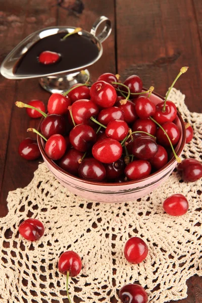 Zralé červené cherry bobule misku a čokoládovou omáčkou na dřevěný stůl detail — Stock fotografie