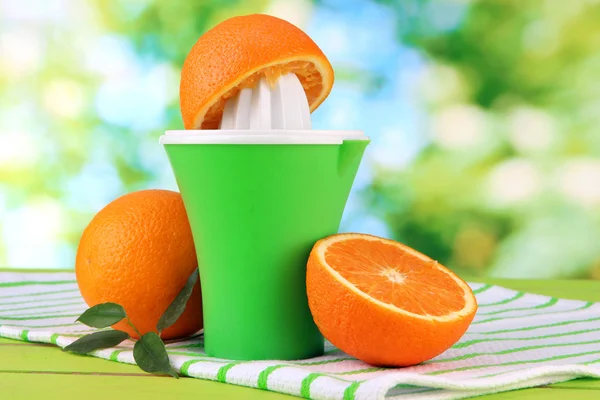 Citrus press and ripe oranges on green wooden table — Stock Photo, Image