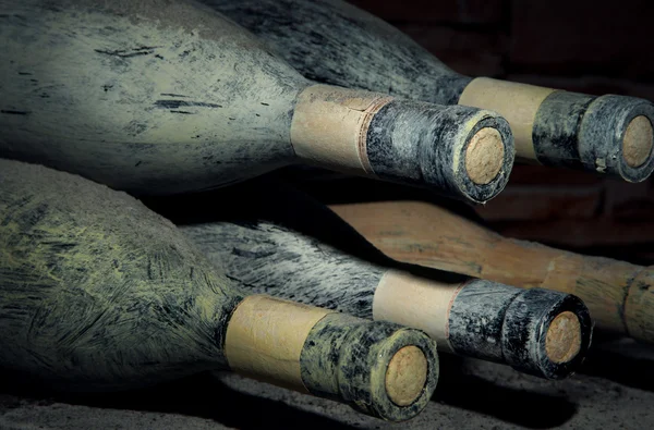 Viejas botellas de vino en bodega vieja, sobre fondo oscuro — Foto de Stock