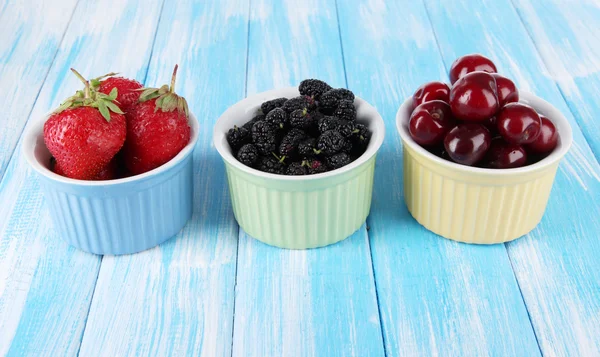 Ripe mulberries with cherry and strawberries in bowls on wooden background — Stock Photo, Image