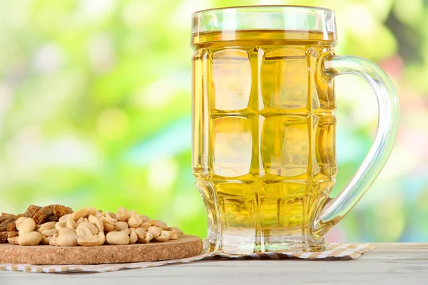Beer in glass crunches, and nuts on napkin on table on nature background background — Stock Photo, Image