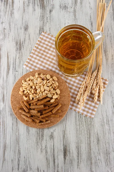 Пиво в хрустящей коробке, орехи на салфетке на деревянном столе — стоковое фото