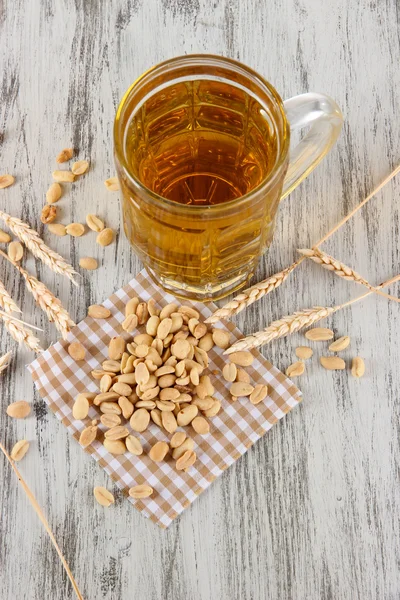 Пиво в стакане и орехи на салфетке на деревянном столе — стоковое фото
