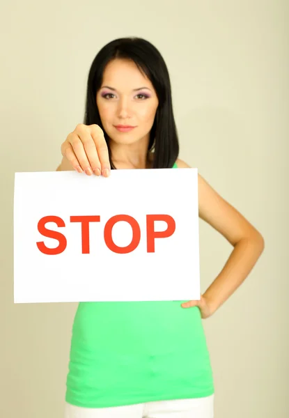 Girl showing stop sign on grey background — Stock Photo, Image